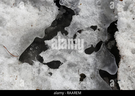 Eine Nahaufnahme der schönen Eisbildung auf einem schwarzen Rock. Durch die Ostsee in Finnland im Winter fotografiert. Stockfoto