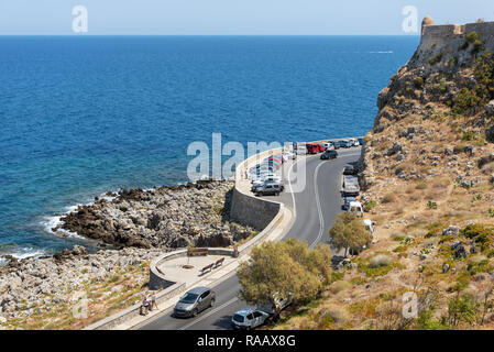 RETHYMNO, Griechenland - AUGUST 2018: Curvy Road mit parkenden Autos entlang der Küste des Mittelmeeres auf der Insel Kreta Stockfoto