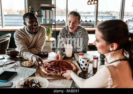 Emotionale international Mensch unter Stück Pizza Stockfoto