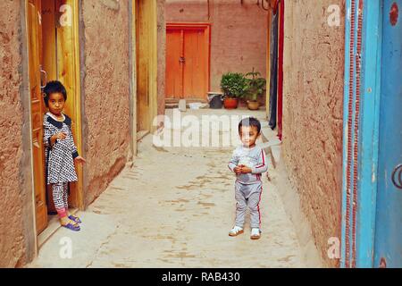 Nicht identifizierte lokalen ethnischen Minderheit islamischer Kinder vor ihrem Haus in renovierten Gebäude in der Altstadt von Kashgar in Xinjiang, China. Stockfoto