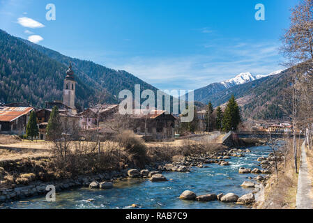 Der Fluss Noce von Hügeln mit schneebedeckten Bergen - Italienische Alpen umgeben. In der Ferne Pellizzano Stadt, Trient, Trentino, Italien Stockfoto