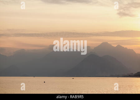 Schöne Skyscape mit ruhigem Meer Wasser und Berge weit weg in der Ferne bei Sonnenuntergang gesehen. Antalya, Türkei, Mittelmeer. Horizontale Stockfoto