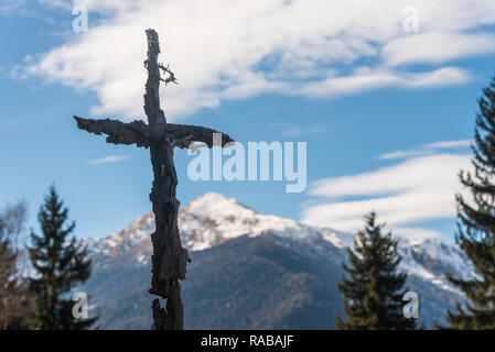 Das Kreuz mit den schneebedeckten Bergen im Hintergrund in Fazzon kleinen Weiler in Val di Sole, Pellizzano, Trient, Trentino, Italien, Europa Stockfoto