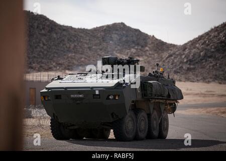 Ein Interim Armored Vehicle (IAV) Stryker trägt Soldaten in einem Dorf während der Übung, NTC-17-03, National Training Center, Ft. Irwin, CA., 18.01.2017. Das National Training Center führt Hart, realistisch, Unified Land arbeiten mit unseren Vereinigte Aktion Partner Brigade Combat Teams und anderen Einheiten für den Kampf vorbereiten, während die Betreuung der Soldaten, Zivilisten, und Familienmitglieder. Stockfoto