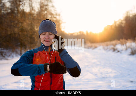 Runner warm tragen sportliche Kleidung in Kopfhörer betrachtet eine moderne Smart Clock Stockfoto