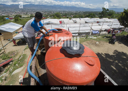 Palu, Sulawesi, Indonesien. 3. Jan 2019. Arbeitnehmer füllen Sie sauberes Wasser für Flüchtlingslager in der Balaroa, Palu, Zentral-sulawesi Dorf integrierte Camp, Indonesien, Donnerstag (1/3/2019). Nach der Eingabe in eine Erweiterung des Notfall- oder drei Monate nach der Katastrophe, Flüchtlinge begann die Schwierigkeit von sauberem Wasser zu fühlen, weil die Versorgung aus der Freiwilligen rückläufig war und in der Zwischenzeit gibt es keine Wasserquellen im Camp. Credit: bmzIMAGES/Alamy leben Nachrichten Stockfoto