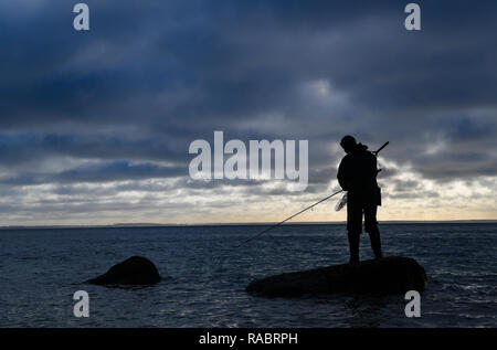 Vitt, Deutschland. 30 Dez, 2018. Ein Angler steht mit einem sich drehenden Stange auf einem Stein in der Ostsee in der Nähe des Fischerdorf Vitt am Kap Arkona. Foto: Patrick Pleul/dpa-Zentralbild/ZB/dpa/Alamy leben Nachrichten Stockfoto