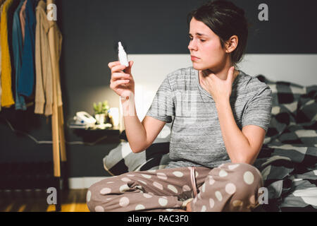 Das Thema saisonale Erkältung, Schnupfen Grippe virus Infektion. Junge kaukasier Frau zu Hause Schlafzimmer Bett verwendet spray Tropfen Medizin an ihre Nase für Sno Stockfoto