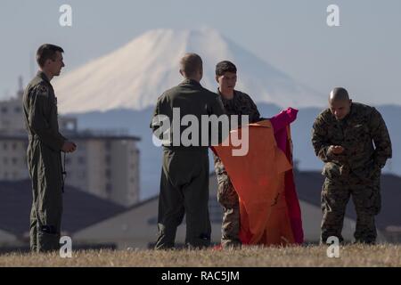 Flieger mit der 36Th Airlift Squadron und Marines mit dem 3 Reconnaissance Bataillon, 3rd Marine Division, III Marine Expeditionary Force ein Winkel Marker an Yokota Air Base, Japan, Jan. 10, 2017. III MEF Marines durchgeführt weeklong springen Ausbildung von einem Air Force C-130 Hercules, die 36 ALS zugewiesen. Die Ausbildung nicht nur erlaubt, die Marines zu springen üben, aber es ist auch erlaubt, die yokota Besatzungen Flug Taktiken zu üben und timed-Paket fällt. Stockfoto