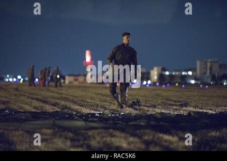 Ein US-Marine Form der 3 Reconnaissance Bataillon, 3rd Marine Division, III Marine Expeditionary Force erholt sich ein Fallschirm nach der Landung am Yokota Air Base, Japan, Jan. 11, 2017, während der Woche springen. Die Ausbildung nicht nur erlaubt, die Marines zu springen üben, aber es ist auch erlaubt, die yokota Besatzungen Flug Taktiken zu üben und timed-Paket fällt. Stockfoto