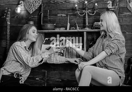 Mädchen entspannende und trinken Glühwein. Freunde auf lächelnde Gesichter in plaid Kleidung zu feiern. Freundschaft Konzept. Freunde in casual Outfits Spaß beim Feiern mit Wein, Interieur aus Holz. Stockfoto