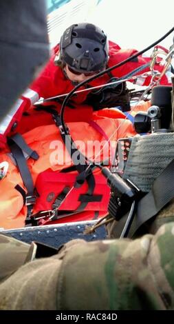 Ein Schutzengel pararescueman aus der uad-2 Rescue Squadron, Guide ein Wurf mit einem zivilen Patienten auf eine HH-60G Pave Hawk Hubschrauber während eines über Wasser Rescue Mission, Jan. 17, 2017. Der kalifornische Nationalgarde aus Die 129 Rettung Flügel ein Personal recovery Mission der schwer kranken 14-jährigen Jungen an Bord eines Kreuzfahrtschiffes, der STAR PRINCESS, etwa 450 Meilen vor der Küste von San Diego, Kalifornien. Stockfoto