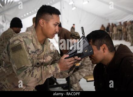 Us-Armee SPC. Chad Fernandez, der 649Th Engineering Firma zugewiesen, 49th Military Police Battalion, nimmt eine retinale Scan eines irakischen Sicherheitskräfte Soldat vor der ISF Ausbildung bei Al Asad Air Base, Irak, Jan. 19, 2017. Al Asad Air Base ist eine von vier Combined Joint Task Force - inhärenten Lösen Standorte für den Aufbau der Kapazitäten der ISF Bereitschaft durch Training zu verbessern. CJTF-OIR ist die globale Koalition zu besiegen ISIL im Irak und in Syrien. Stockfoto