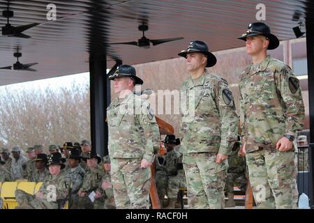 Oberstleutnant John govan III (links), scheidender Kommandeur, 115 Brigade Support Battalion Muleskinners", 1st Armored Brigade Combat Team, 1.Kavallerie Division, bereitet der Verzicht auf Befehl des Bataillons Oberstleutnant Eric Christiansen (rechts), während eine Änderung der Befehl Zeremonie an der Cooper Feld Jan. 18 in Fort Hood, Texas. Überprüfen der Offizier Oberst John DiGiambattista (Mitte), Commander, 1 ABCT, akzeptiert das BATAILLON Farben von Govan während der Zeremonie und übergeben sie an Christiansen, symbolisch an den Mantel der Befehl für das Bataillon zu Christiansen. Stockfoto