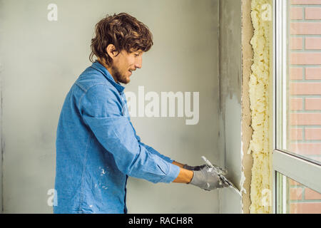 Master ist die Anwendung weiß putty an einer Wand und Verschmieren von Spachtel in einem Zimmer renovieren Haus tagsüber Stockfoto