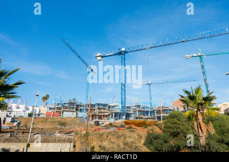 Eine Baustelle mit blauen Krane und unvollendete Gebäude, Wohnung Komplex, Benalmadena, Spanien. Stockfoto