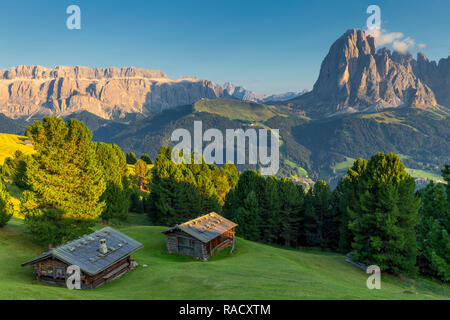 Letzten Strahlen der Sonne auf traditionelle Hütten mit Blick auf den Langkofel und Sella Gruppe, Grödnertal, Südtirol, Dolomiten, Italien, Europa Stockfoto