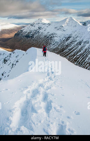 Eine weibliche Walker Abstieg vom Gipfel des Stob Dubh auf Buchaille Etive Beag an einem klaren Wintertag, Highlands, Schottland, Großbritannien, Europa Stockfoto