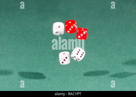 Vier rote und weisse Würfel fallen auf einem grünen Tisch Stockfoto