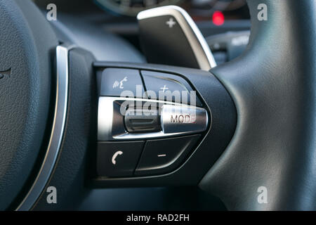 Nahaufnahme eines modernen Autos Lenkrad mit Tasten zur Mediensteuerung und Gangwechsel stick, Innenraum Details Stockfoto