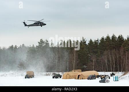 Grafenwöhr, Deutschland - EIN UH-60A/L Blackhawk Hubschrauber von C Company, 1-214 th Allgemeine Unterstützung Aviation Battalion fliegt über die Zelte und Fahrzeuge des 67., OP-Team, Jan. 10, 2017. Stockfoto