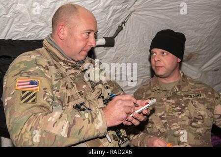 Grafenwöhr, Deutschland - Sgt. Tschad F. Salinero, ein Flug medic mit C Company, 1-214 th Allgemeine Luftfahrt, erhält Bericht über einen simulierten Unfall von Maj. Joshua A. Scott, eine allgemeine Chirurg mit 67 Vorwärts OP-Team, vor aeromedical Evacuation, Jan. 11, 2017. Stockfoto