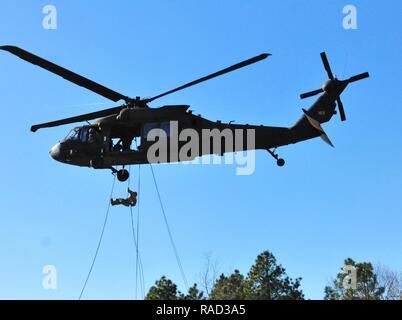 Die Kursteilnehmer auf das XVIII Airborne Corps' DeGlopper Air Assault School, Fort Bragg, N.C. zugewiesen sind, nehmen an den Air Assault Ausbildung Jan. 25, 2017. Die Ausbildung ist der Mähdrescher mit rappel Techniken von einem UH-60 Black Hawk, wie es schwebt 100 Fuß auf Simmons Flugplatz. Stockfoto