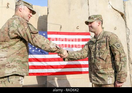 Oberstleutnant John Hawbaker, Kommandant der 1. Staffel, 73 Cavalry Regiment, 2nd Brigade Combat Team, 82nd Airborne Division, gratuliert Sgt. Patrick R. Bradford, ein infanterist, nach seiner dreijährigen reenlistment bei Qayyarah West, Irak, Jan. 26, 2017. Zur Unterstützung der Operation inhärenten lösen, die 2 BCT eingesetzt, 82. Abn. Div. ermöglicht, ihre irakische Sicherheitskräfte, die Partner durch den beraten und unterstützen die Mission, die die Planung, Erfassung und Analyse von Intelligenz, Kraft und Präzision Brände die militärische Niederlage der ISIL zu erreichen. Stockfoto