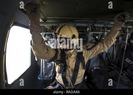 Eine US-Zoll und Grenzschutz, Luft und Marine Operations Air Interdiction Agent hält sich an den obenliegenden griffen während eines Fluges in einem UH-60 Black Hawk Hubschrauber während einer Luft-Achsenabschnitt Übung wie sie Luftraum Super Bowl LI in Conroe, Texas, 1. Februar 2017 abzusichern. Einheiten mit Luft und Marine Operations und Office of Field Operations teamed oben mit der Civil Air Patrol, eine Luft/Luft-abfangen mit zwei AMO UH-60 Black Hawk Hubschraubern zu üben und zwei C-550 Citation Jets auf die Spur einer simulierten Einfall in eingeschränkten Luftraum. Ein zusätzlicher Flug wurde Stockfoto