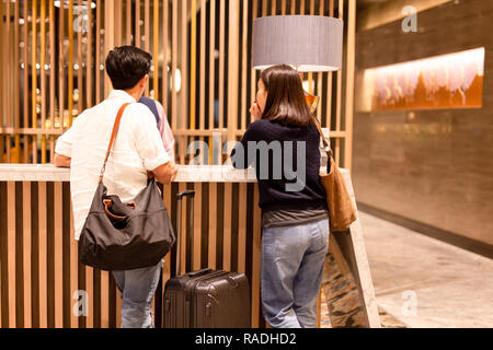 Asiatische Paar mit Koffer Einchecken an der Hotelrezeption. Stockfoto