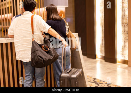 Asiatische Paar mit Koffer Einchecken an der Hotelrezeption. Stockfoto