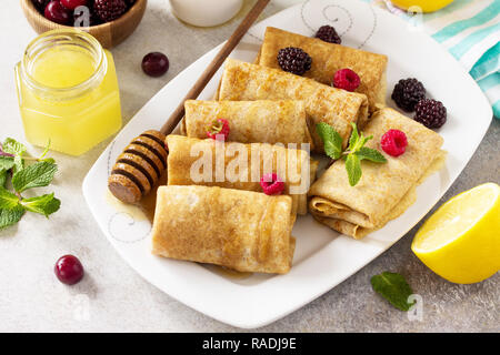 Gesunde Pfannkuchen Frühstück. Stapel von hausgemachten dünne Pfannkuchen oder Crepes Vollkornmehl, mit Honig und frischen Beeren serviert. Stockfoto