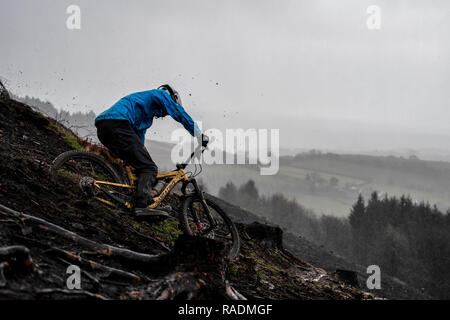 Ein Mountainbike sendet Schlamm Spritzen in die Luft, eine Spur an einem regnerischen Winter in South Wales. Stockfoto