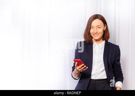 Schöne Geschäftsfrau holding red Handy Porträts Stockfoto