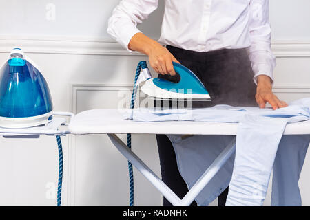 Woman's Hand Dampf Bügeleisen und -Shirt Stockfoto