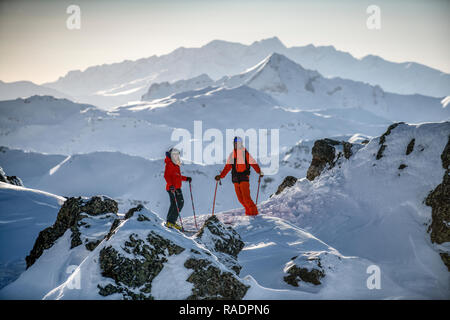 Zwei Skifahrer stehen auf einem Bergrücken oberhalb Courchevel mit Blick über die drei Täler Skigebiet in den Französischen Alpen. Stockfoto