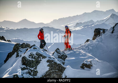 Zwei Skifahrer stehen auf einem Bergrücken oberhalb Courchevel mit Blick über die drei Täler Skigebiet in den Französischen Alpen. Stockfoto