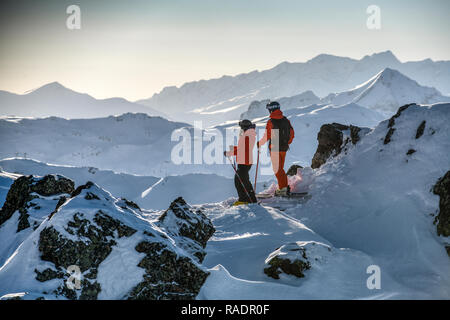 Zwei Skifahrer stehen auf einem Bergrücken oberhalb Courchevel mit Blick über die drei Täler Skigebiet in den Französischen Alpen. Stockfoto