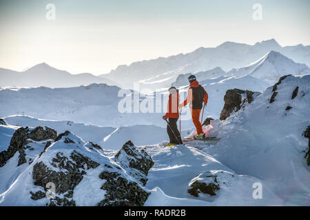 Zwei Skifahrer stehen auf einem Bergrücken oberhalb Courchevel mit Blick über die drei Täler Skigebiet in den Französischen Alpen. Stockfoto