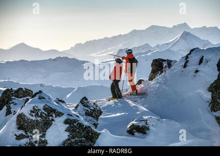 Zwei Skifahrer stehen auf einem Bergrücken oberhalb Courchevel mit Blick über die drei Täler Skigebiet in den Französischen Alpen. Stockfoto