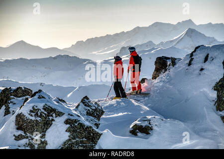 Zwei Skifahrer stehen auf einem Bergrücken oberhalb Courchevel mit Blick über die drei Täler Skigebiet in den Französischen Alpen. Stockfoto