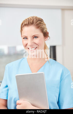Lächelnde Frau als Krankenschwester mit Tablet Computer im Krankenhaus Stockfoto