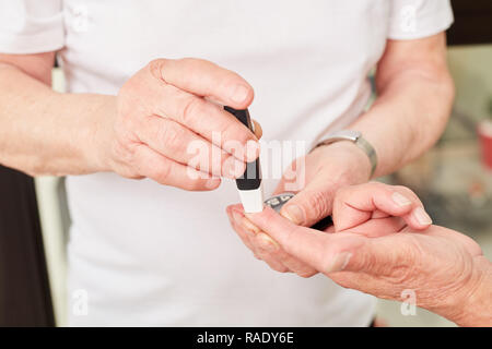 Blutzucker Messung in Diabetes auf der Finger auf der Hand einer älteren Person Stockfoto