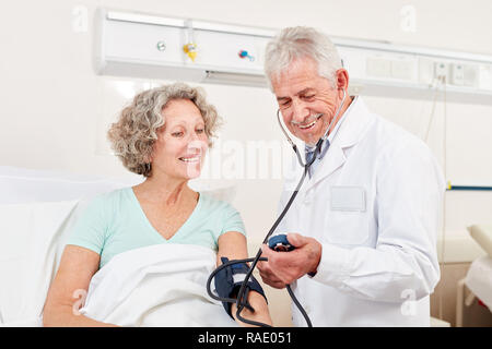 Erfahrenen Arzt prüft den Blutdruck eines Patienten im Krankenhaus Stockfoto