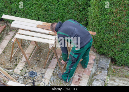 Mann mit einem Pinsel streichelte Holzbalken. Stockfoto