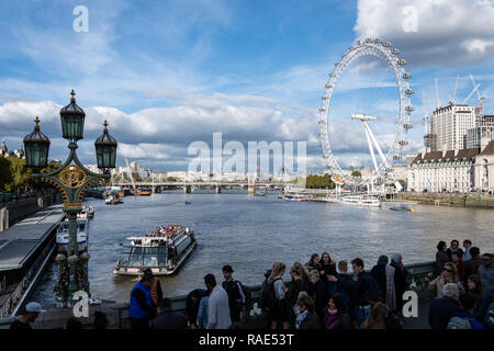 London, Großbritannien, 18. Oktober 2018: Massen von Touristen Blick nach Westen entlang der Themse vom Westminster Bridge mit einem Boot den pie Stockfoto