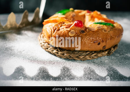 Nahaufnahme eines roscon de Reyes, drei Könige Kuchen auf epiphanie Tag gegessen Spanisch, auf einem grauen rustikalen Tisch Stockfoto