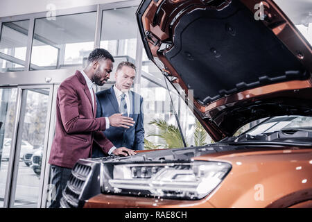 Reifen gut aussehender Geschäftsmann in der Nähe von Berater vor dem Kauf Auto Stockfoto