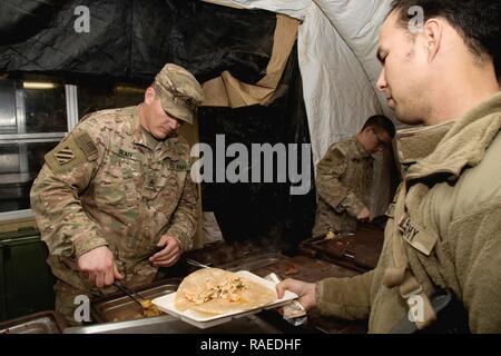 U.S. Army Staff Sgt. Matthew T. Dean, eine kulinarische Spezialisten, auf das erste Bataillon zugeordnet, 67th Armored Regiment, 3. gepanzerte Brigade Combat Team, 1. Panzerdivision, serviert Speisen an Soldaten beim Abendessen in der Nähe von Keramlais, Irak, Jan. 28, 2017. Kulinarische Spezialisten bieten warme Mahlzeiten für die Soldaten, die Unterstützung von Combined Joint Forces Land Component Command-Betrieb inhärenten Lösen. CJTF-OIR ist die globale Koalition zu besiegen ISIS im Irak und in Syrien. Stockfoto