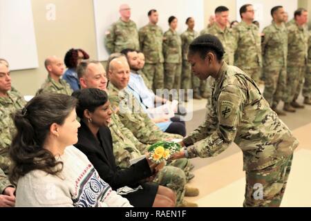 Sgt. Kamirah Williams, rechts, Hände einen Strauß gelber Blumen in Nikia Trotter in der Übernahme von Verantwortung, in der Trotter's Mann, Command Sgt. Maj. Peter Traber, wurde die United States Army zivilen Angelegenheiten und psychologische Operations Command (Airborne) ältere Soldaten leader Dez. 15, 2018 an der USACAPOC (A) Hauptquartier in Fort Bragg, N.C. Stockfoto